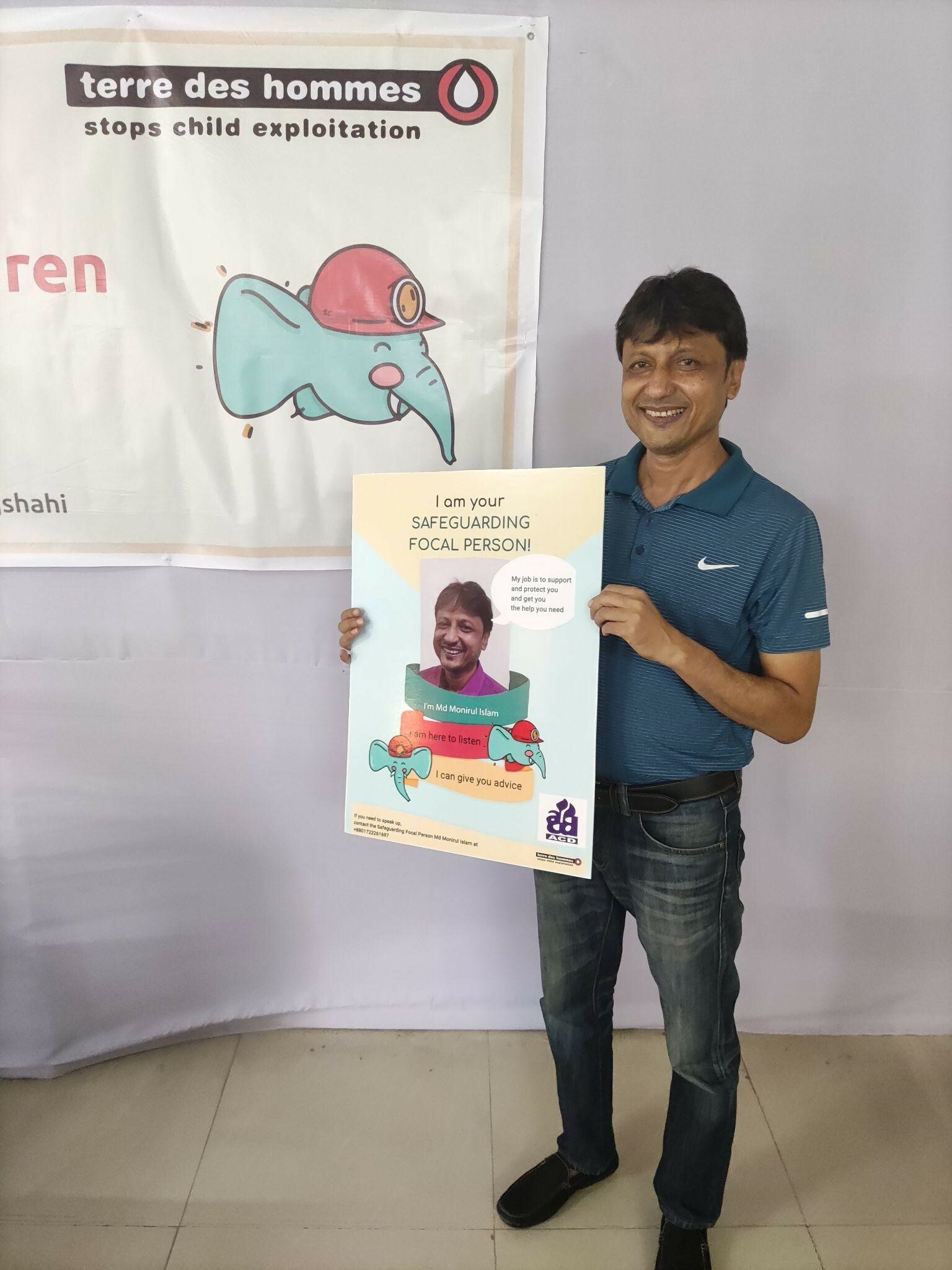 Figure 3. A social worker from Association for Community Development in Bangladesh, holding a poster announcing him as someone who is there to listen to children as the safeguarding focal point (picture taken and shared with consent).